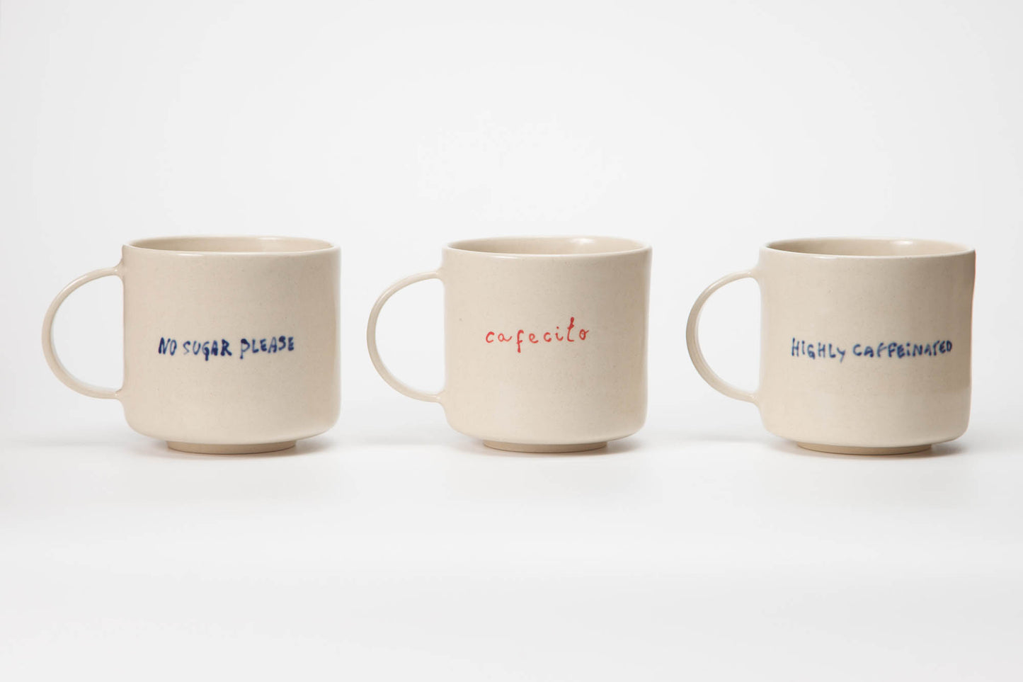 Three ceramic mugs with text on a white background