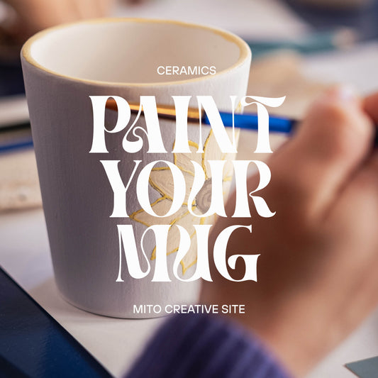 Pottery Painting Workshop in Lisbon, Portugal. A close-up of a hand holding a paintbrush beside a ceramic mug, with large overlaid text reading 'PAINT YOUR MUG'