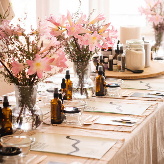 Table setting with floral arrangements, bottles, and stationery items.