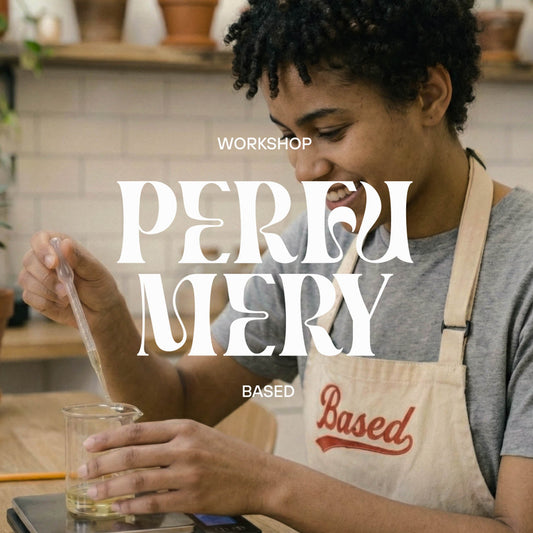 A person in a kitchen or workshop setting wearing a beige apron with the word 'Based' in red script, holding a glass beaker and using a dropper. Large overlaid text reads 'PERFUMERY WORKSHOP MADRID'.