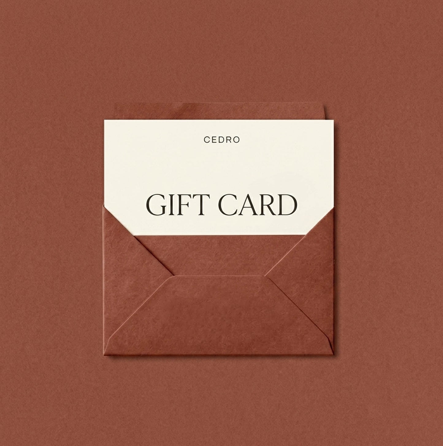 A Cedro gift card with a cream-colored paper insert and black text, partially tucked inside a brown envelope on a matching brown background.