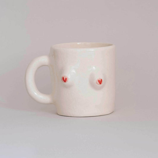 White ceramic mug with red heart designs on a light gray background