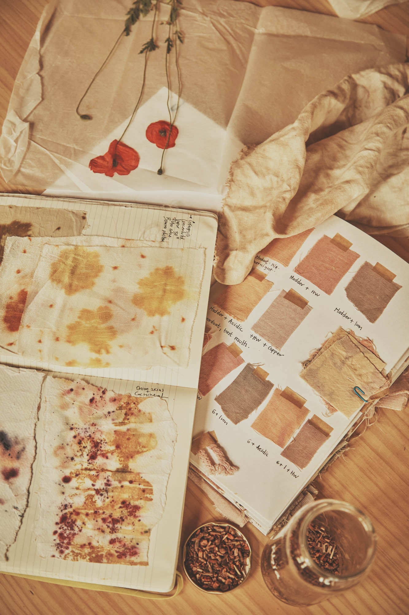 Open book with color swatches and dried flowers on a wooden surface