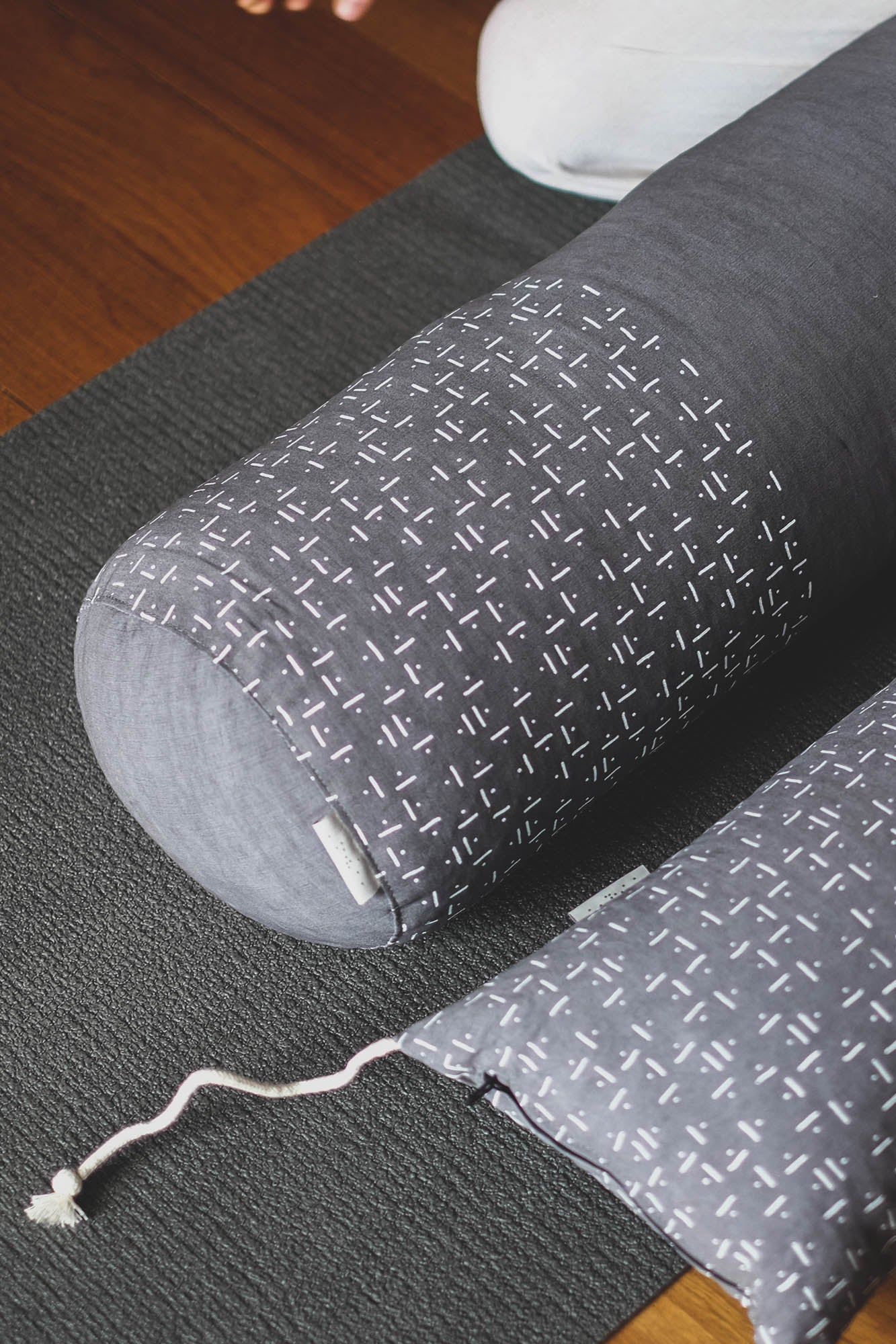 Yoga bolster and meditation cushion set over mat.