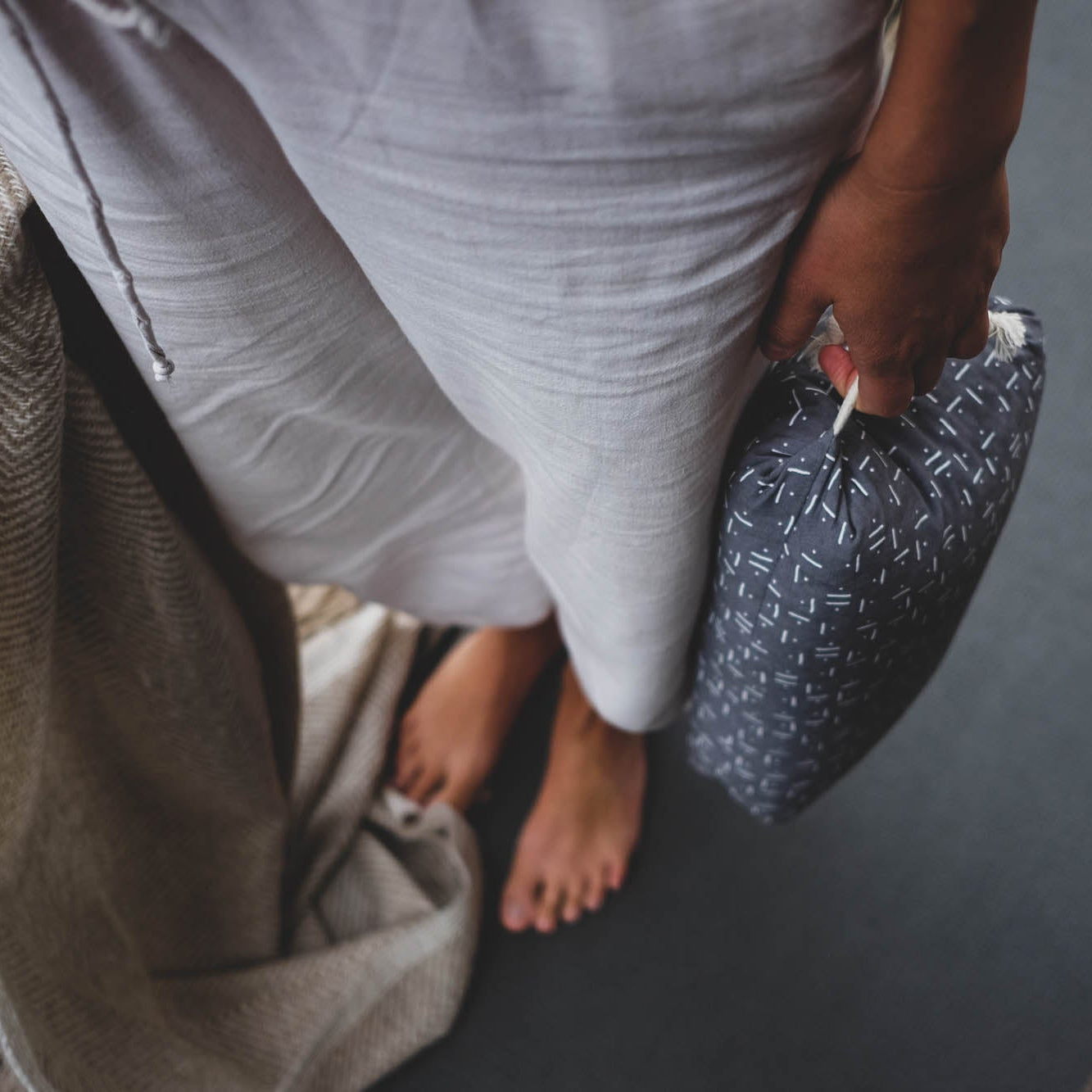 Person holding a patterned pillow on a wooden floor