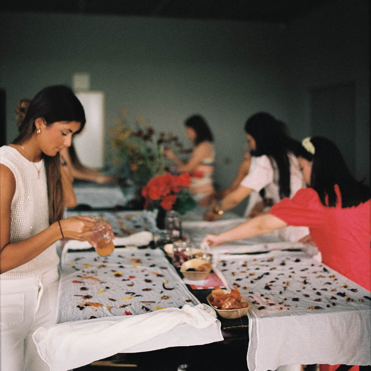 Group of women sitting around a table with food and drinks, engaged in conversation.