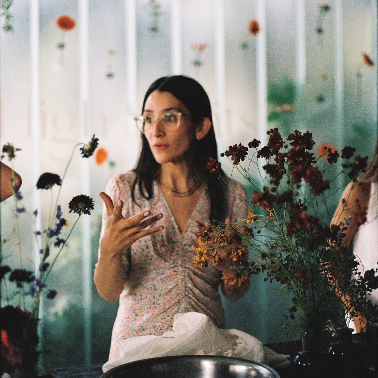 Woman teaching natural botanical dye  workshops with flowers in a room with floral curtains, corporate event.