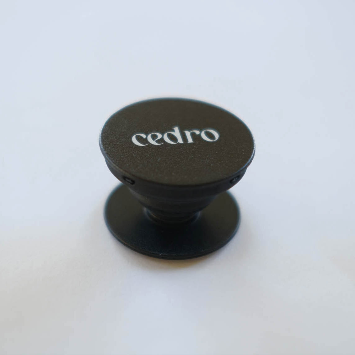 Black phone holder with 'cedro' branding on a white background