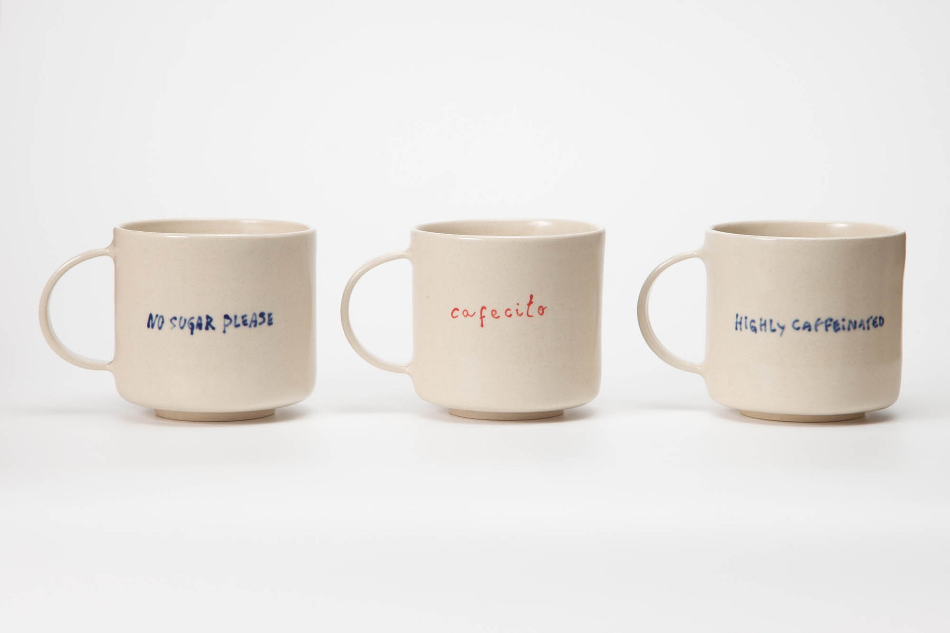 Three ceramic mugs with text on a white background