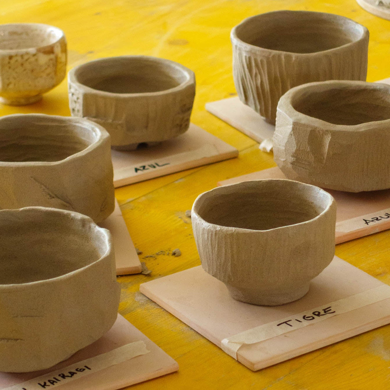 Set of ceramic bowls on a yellow surface with labels underneath