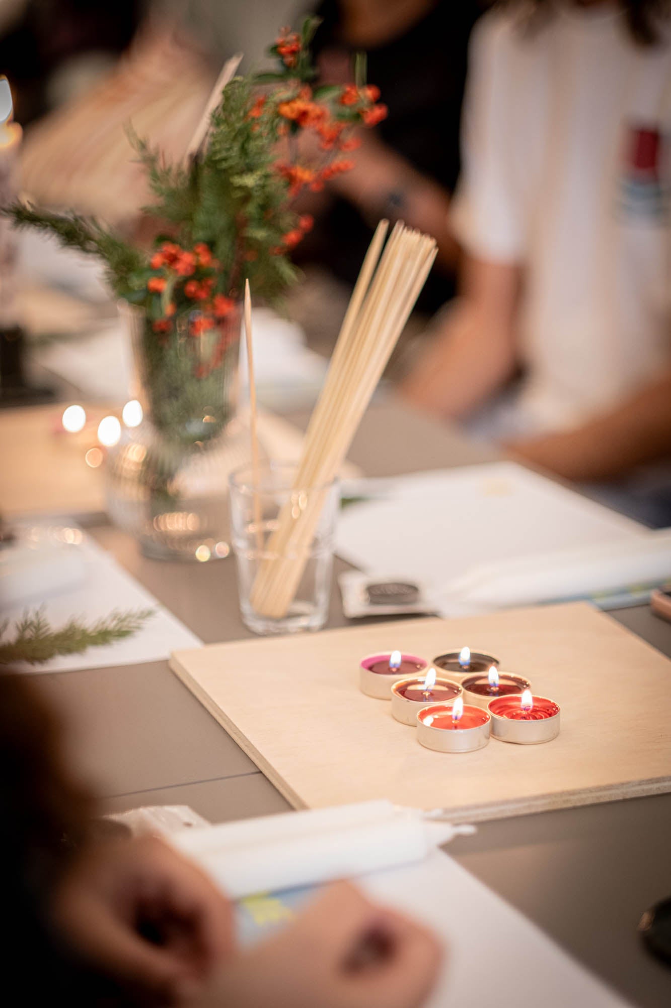 Table setting with candles, a vase of flowers, and a person in the background.