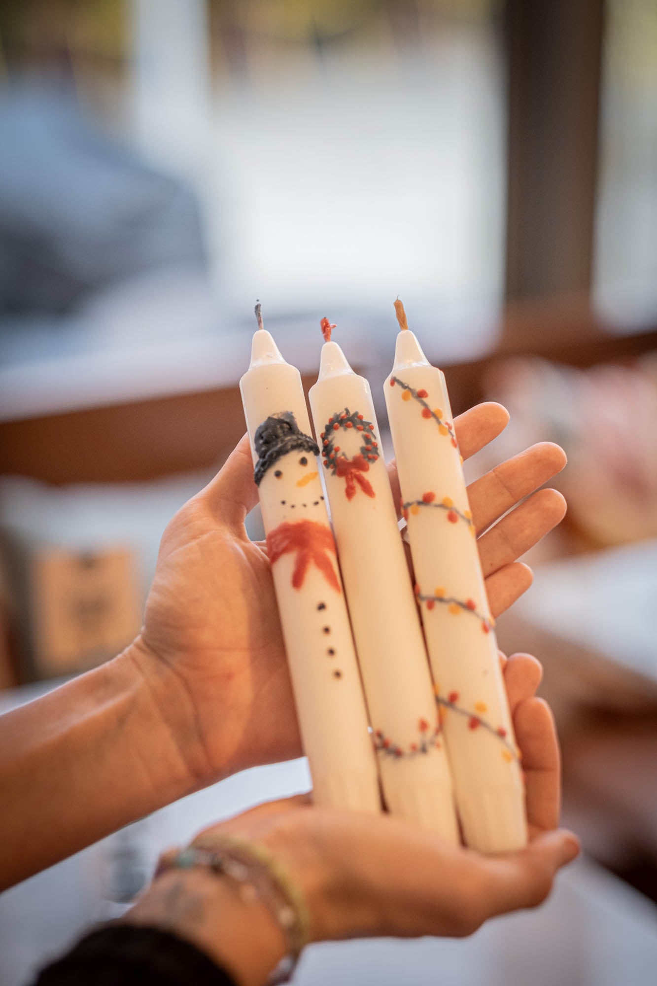 Hand holding three x-mas decorated candles with a blurred background