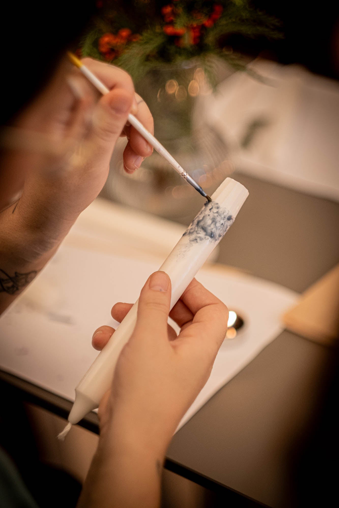 Person applying a white substance to a cylindrical object with a brush, possibly in a kitchen setting.