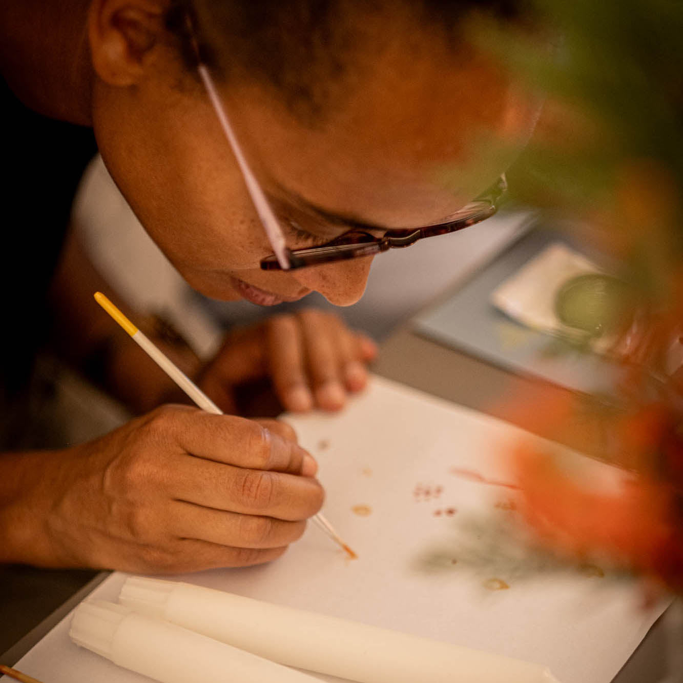 Person painting with a brush on a piece of paper
