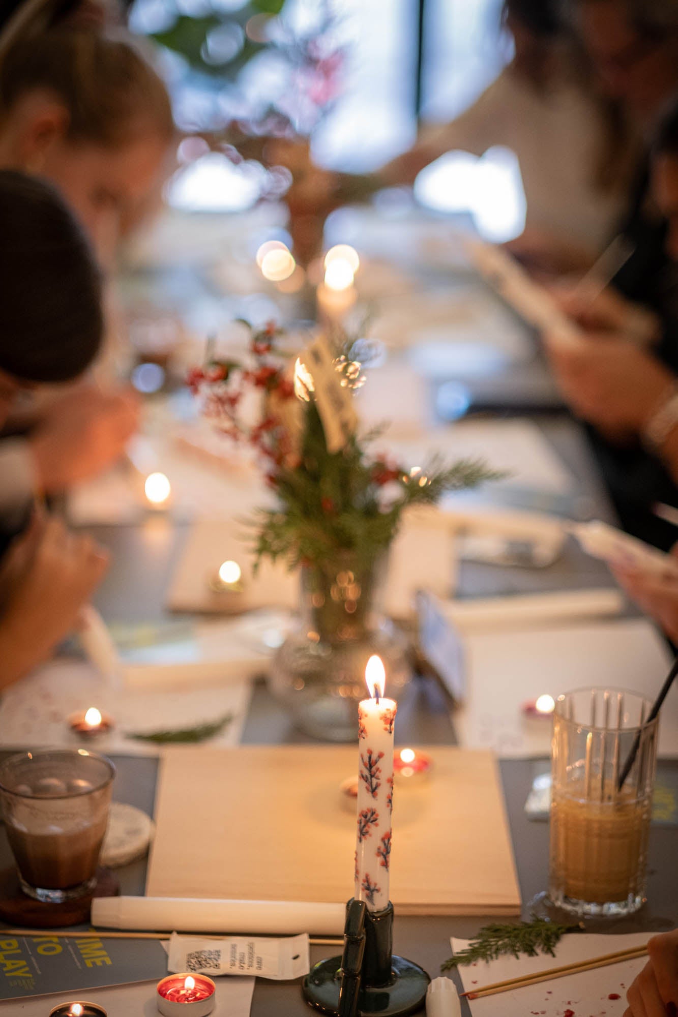 Dining table with candles, brushes, and a vase of flowers in a softly lit setting.