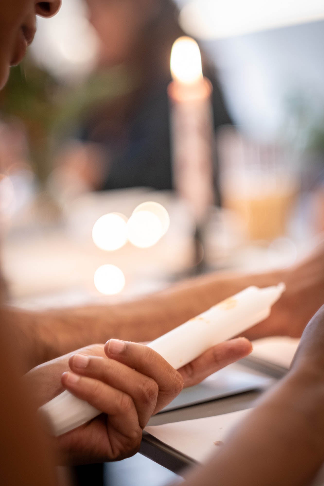 Close-up of hands holding a lit candle with a blurred background