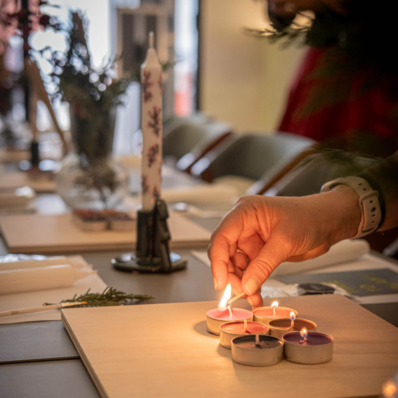 Person lighting small candles on a wooden board with a blurred background