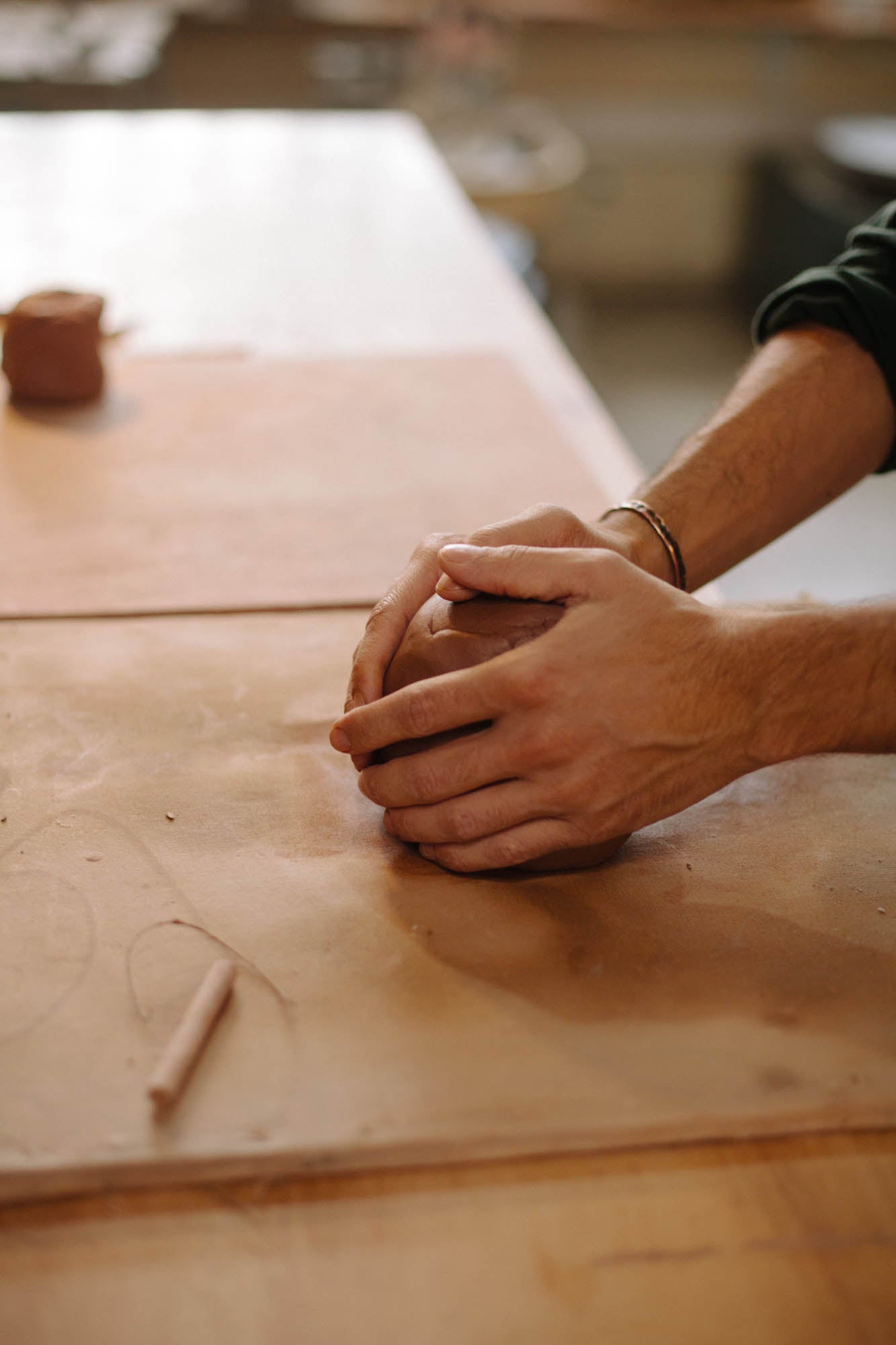Person's hands working with clay on a wooden surface