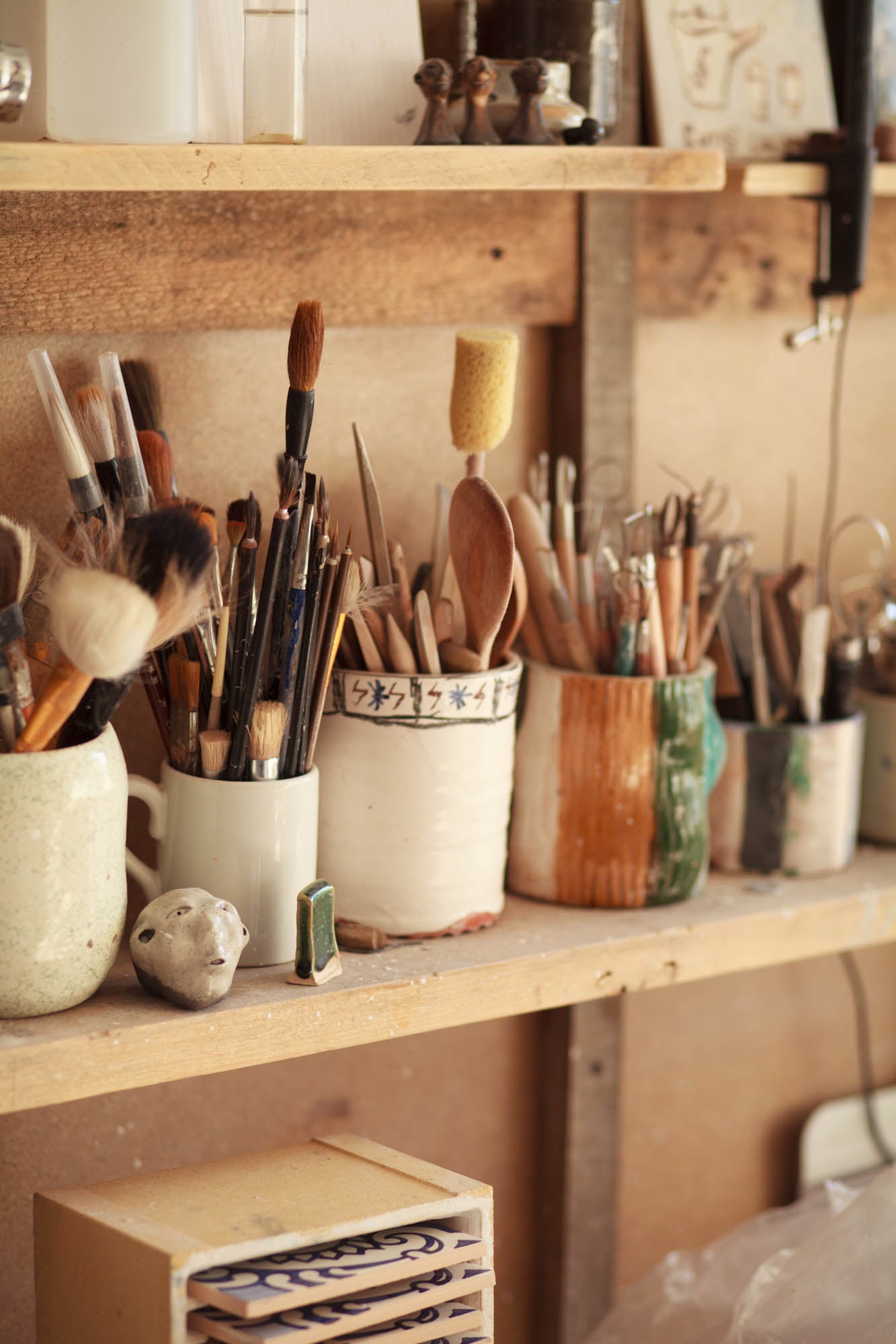 Workshop setting with various art supplies on wooden shelves.