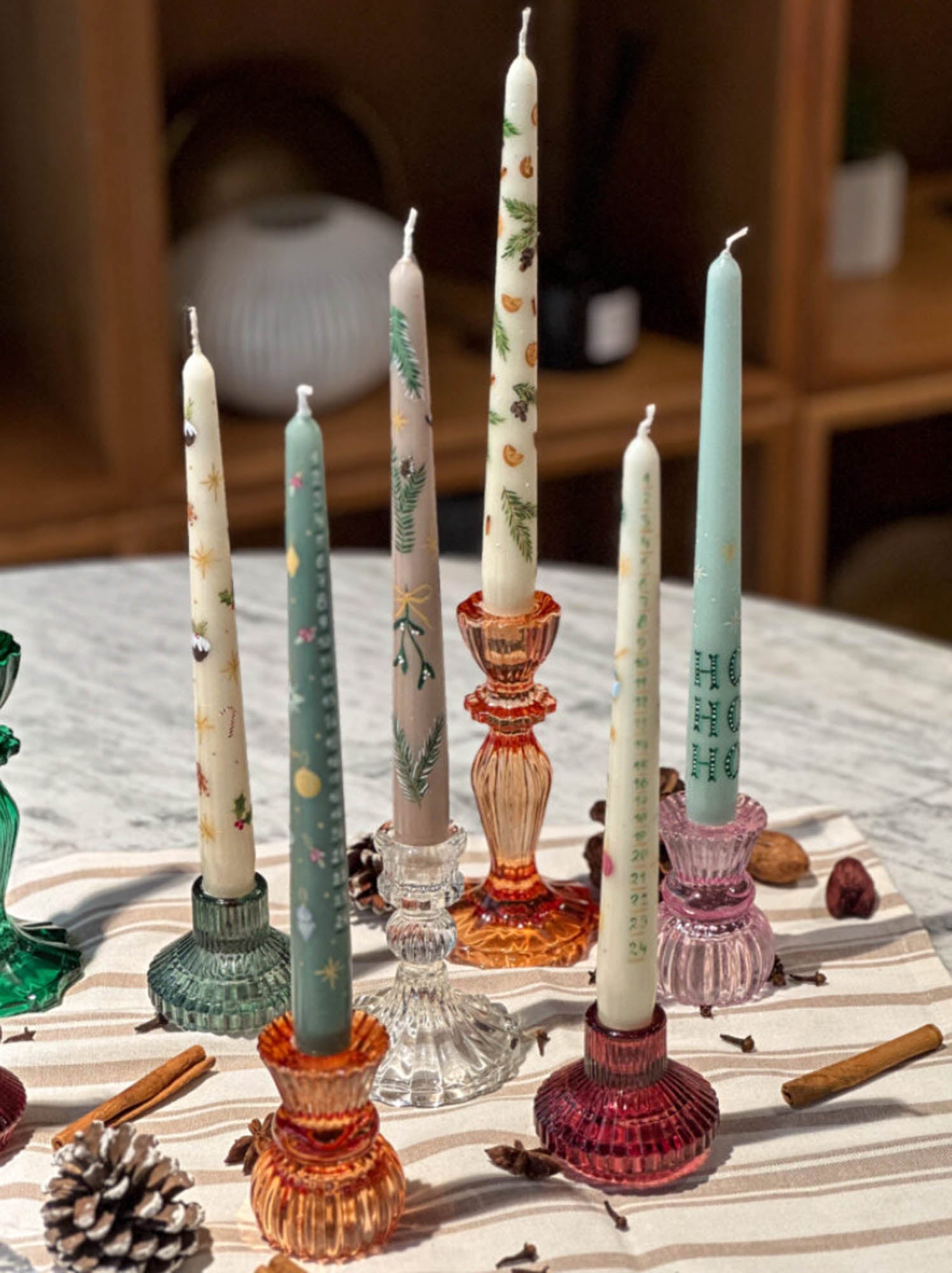 Decorative candles in various holders on a table with a wooden background