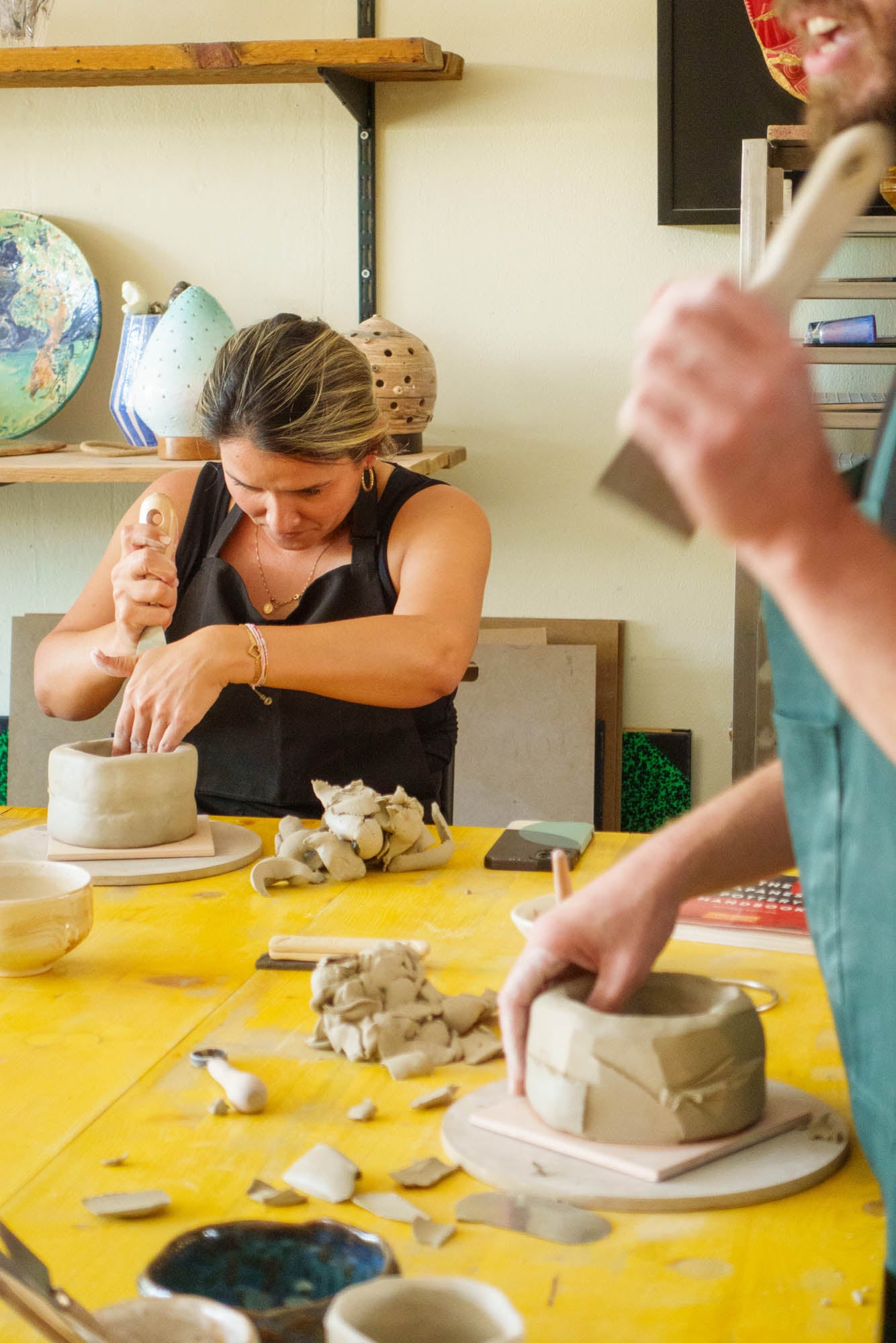 Two people working with clay in a pottery studio.