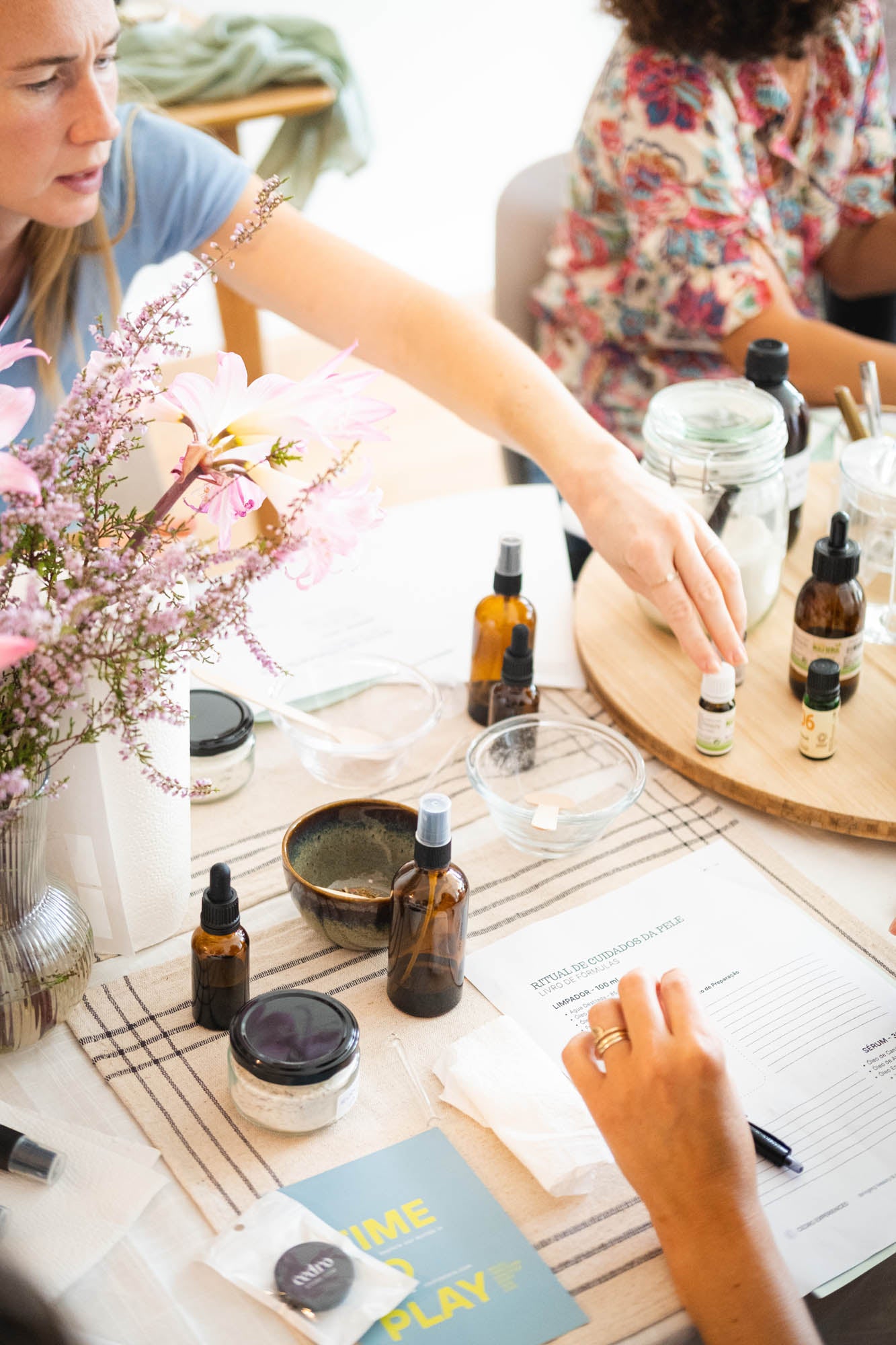 People at a table with essential oil bottles and a notebook