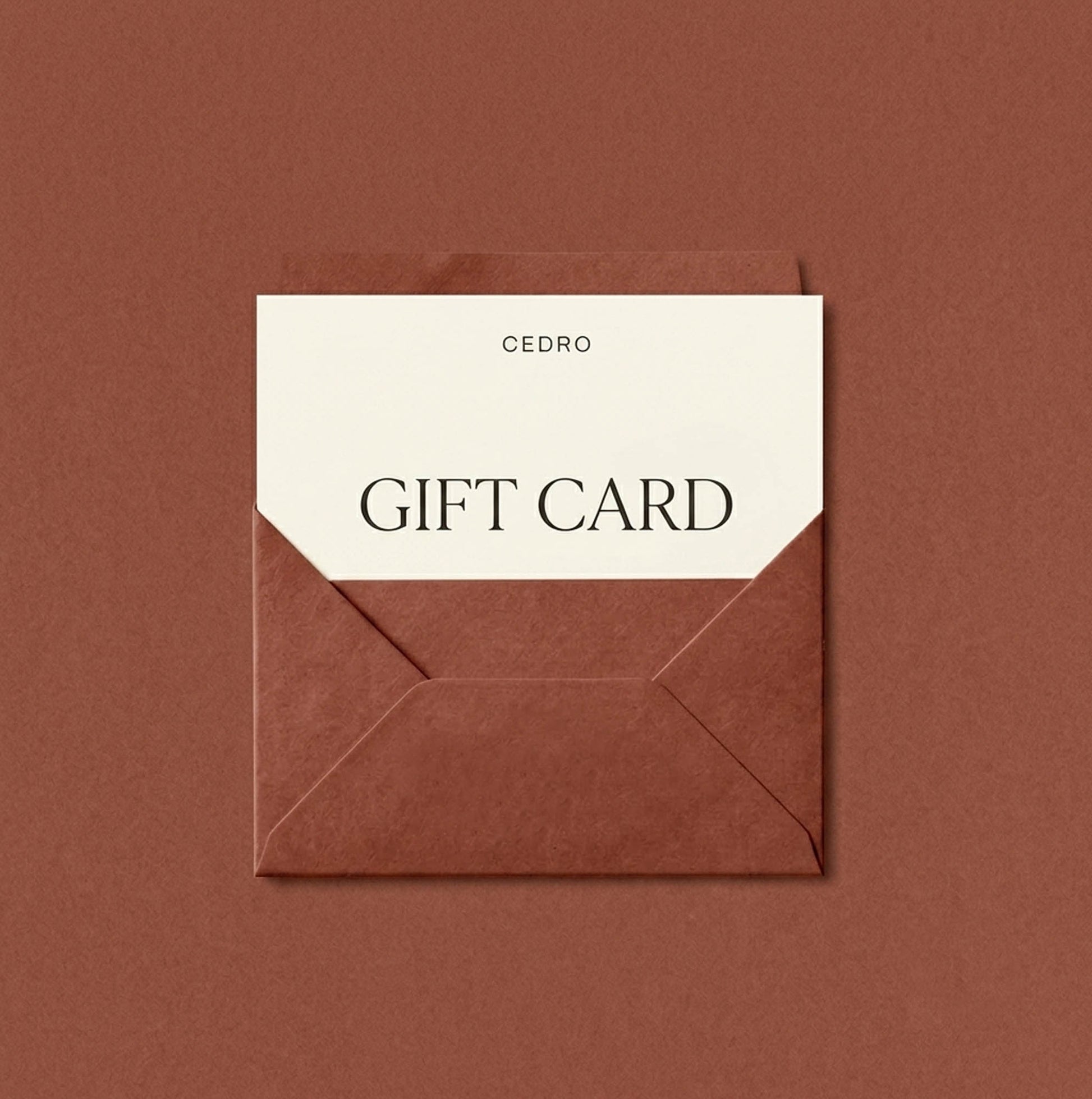 A Cedro gift card with a cream-colored paper insert and black text, partially tucked inside a brown envelope on a matching brown background.