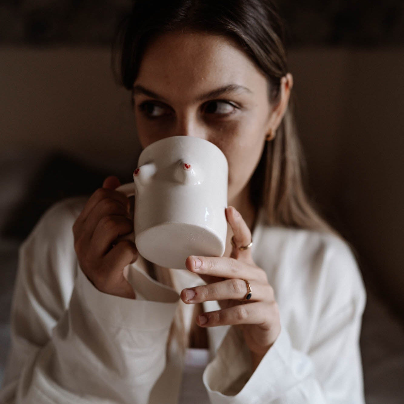 Woman holding a white ceramic piggy bank against a blurred background