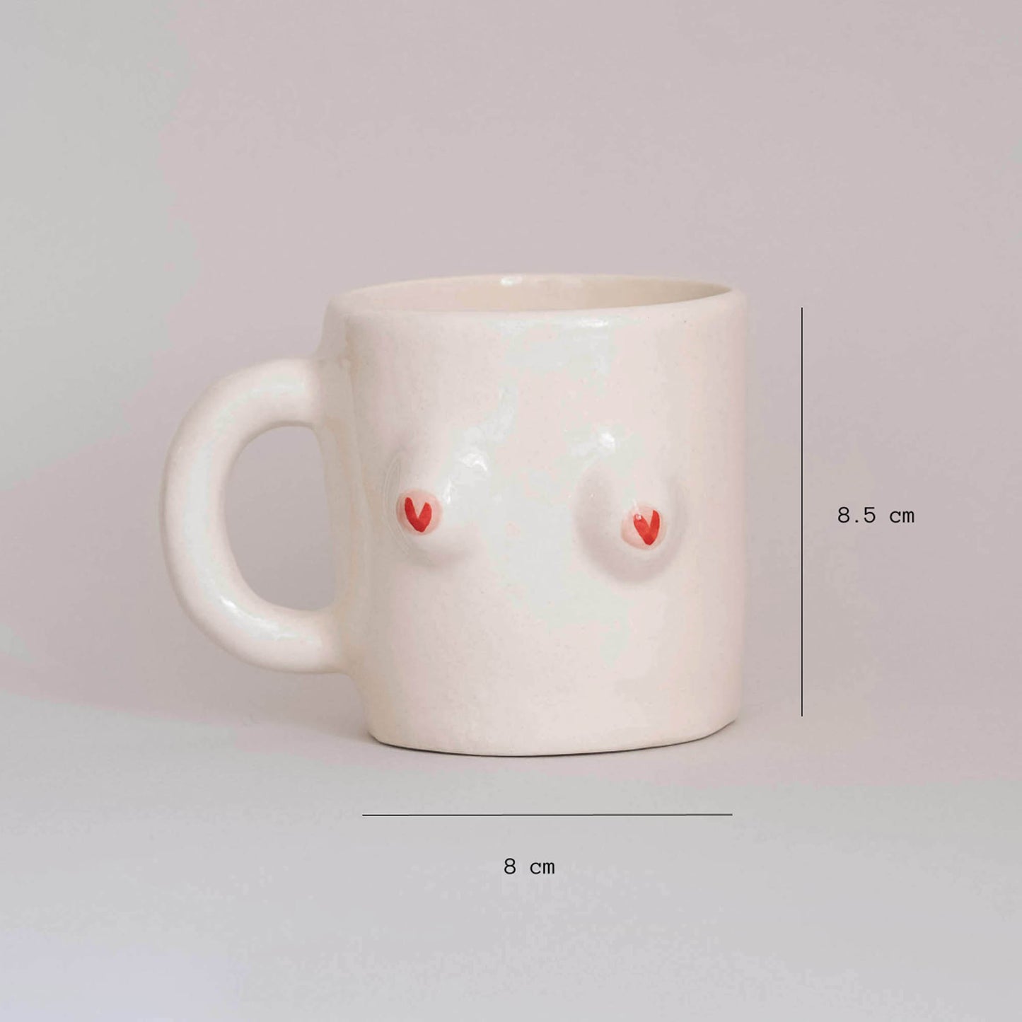White ceramic mug with red heart designs on a light gray background. Breast mug. Boobs mug.